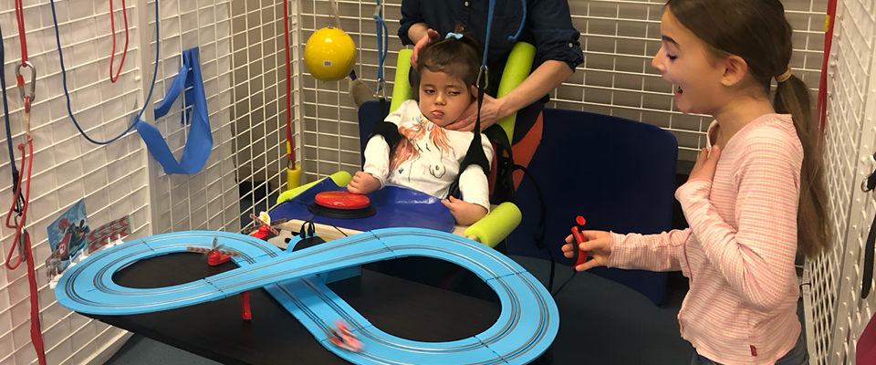 Two children, one in a wheelchair, play with adaptive slot cars together