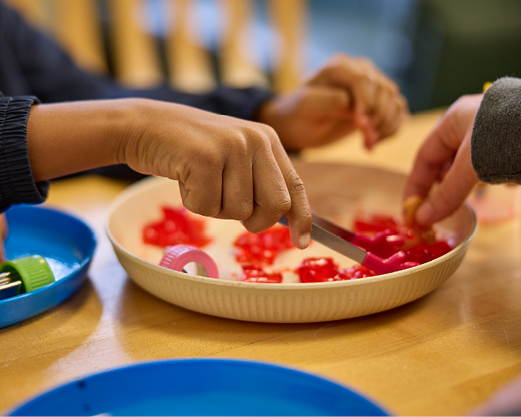 A baby girl wearing a large tan bow on her head is chewing on a Nuk brush as part of occupational therapy.