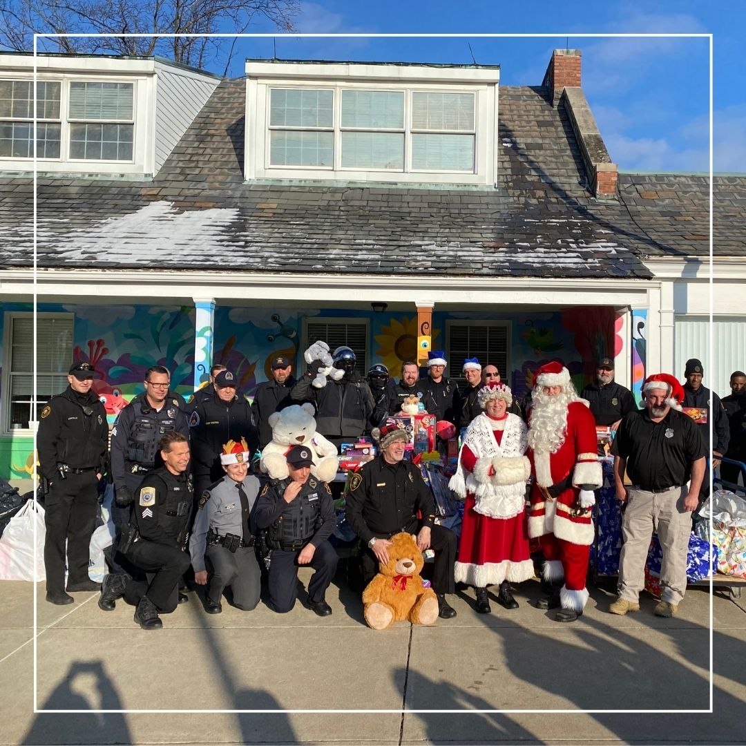 Presents from Police officers pose with Santa and Mrs. Claus in front of The Day School.