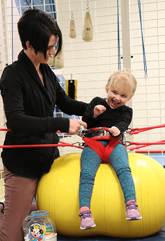 Patient with Occupational Therapist in Universal Exercise Unit (UEU) performing pediatric occupational therapy